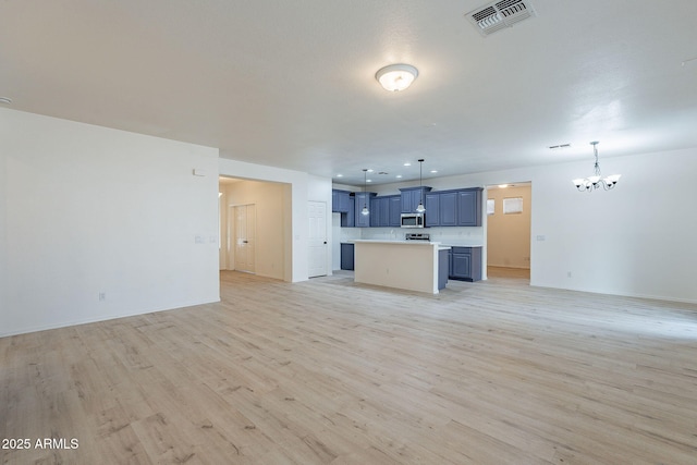 unfurnished living room featuring light hardwood / wood-style floors and an inviting chandelier