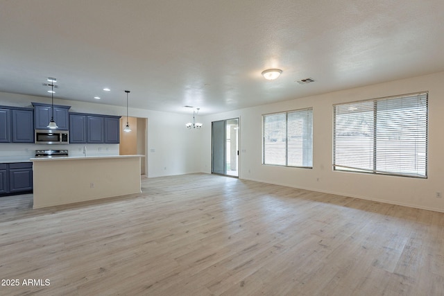 unfurnished living room with light wood-type flooring and an inviting chandelier