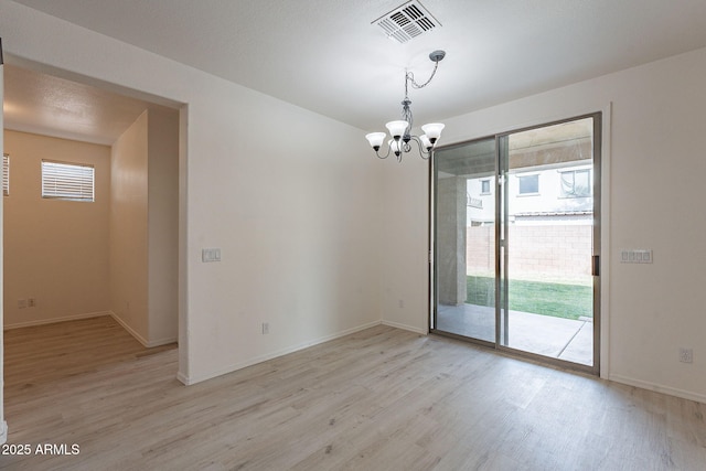 unfurnished room featuring a notable chandelier and light hardwood / wood-style flooring