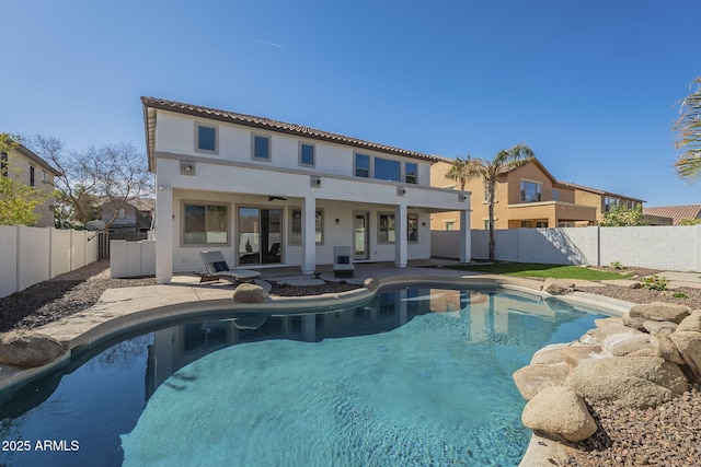 back of house featuring a fenced in pool, a patio area, a fenced backyard, and stucco siding