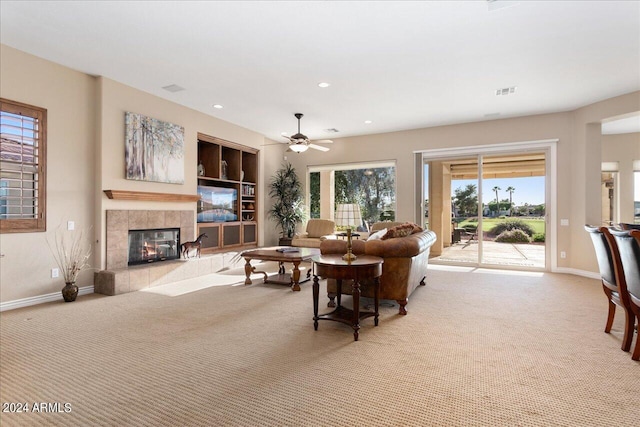 carpeted living room featuring a fireplace, ceiling fan, and plenty of natural light