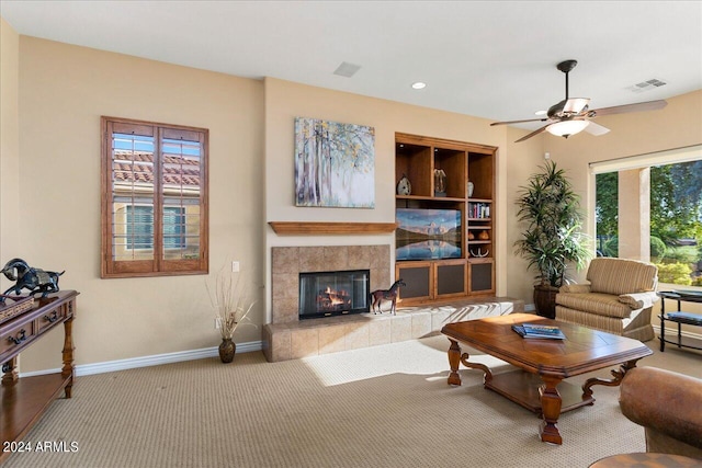 living room featuring a fireplace, light colored carpet, and ceiling fan