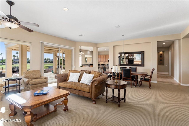 living room featuring ceiling fan with notable chandelier and light carpet