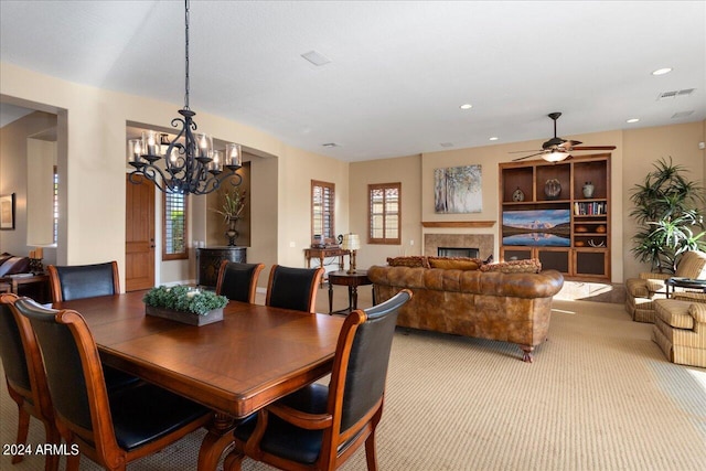 dining space with ceiling fan with notable chandelier and light colored carpet