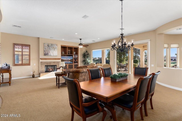 dining space with a premium fireplace, light colored carpet, and ceiling fan with notable chandelier