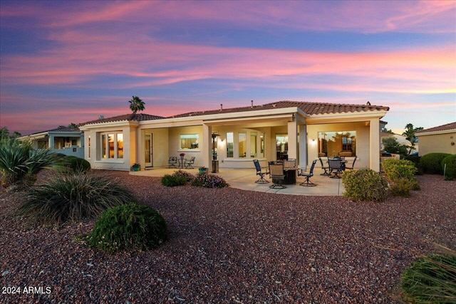 back house at dusk featuring a patio area