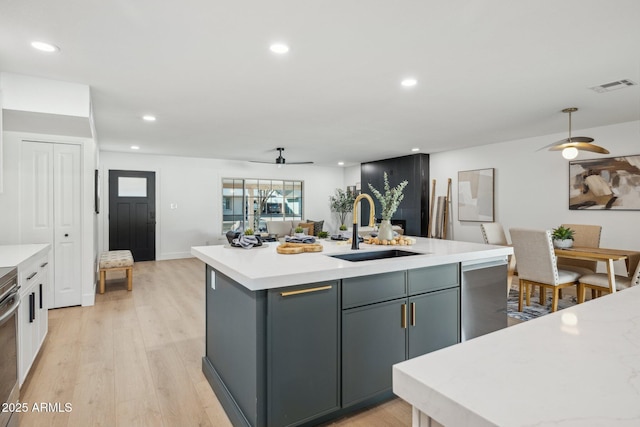 kitchen featuring sink, gray cabinetry, a kitchen island with sink, ceiling fan, and light hardwood / wood-style flooring