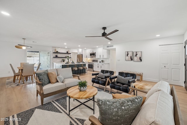 living room with ceiling fan and light wood-type flooring