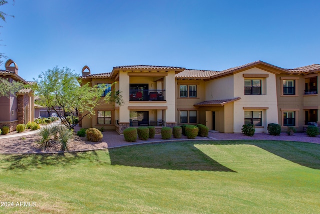 mediterranean / spanish-style home with a balcony and a front lawn