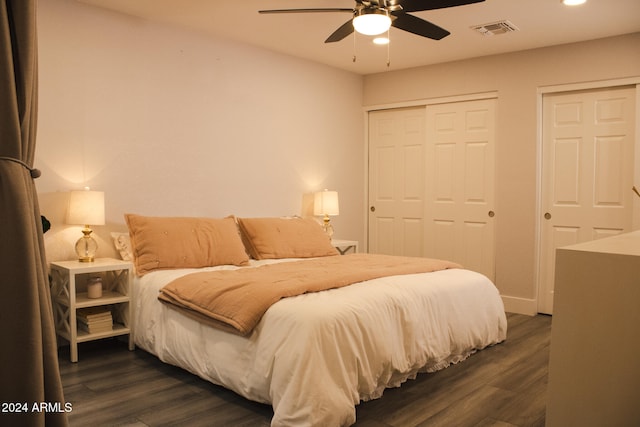 bedroom with multiple closets, ceiling fan, and dark hardwood / wood-style floors