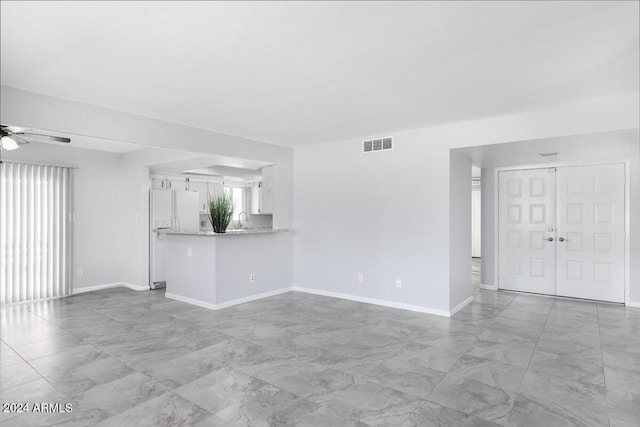 unfurnished living room featuring ceiling fan and sink