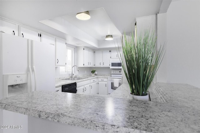 kitchen featuring kitchen peninsula, white appliances, a tray ceiling, sink, and white cabinetry