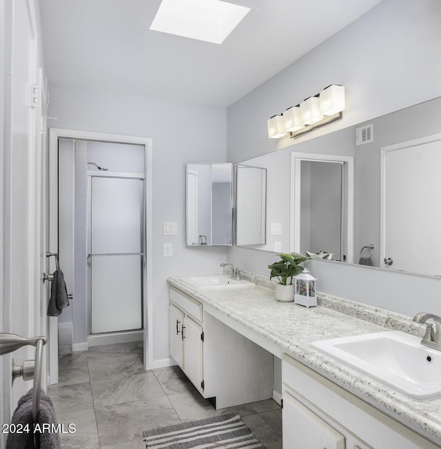 bathroom with vanity, a shower with shower door, and a skylight