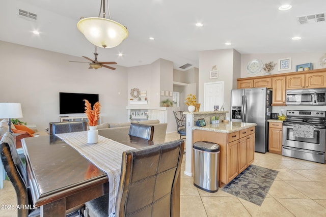 kitchen with decorative light fixtures, vaulted ceiling, light tile patterned floors, appliances with stainless steel finishes, and a kitchen island