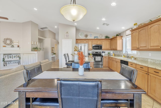 kitchen featuring sink, vaulted ceiling, light tile patterned floors, pendant lighting, and stainless steel appliances