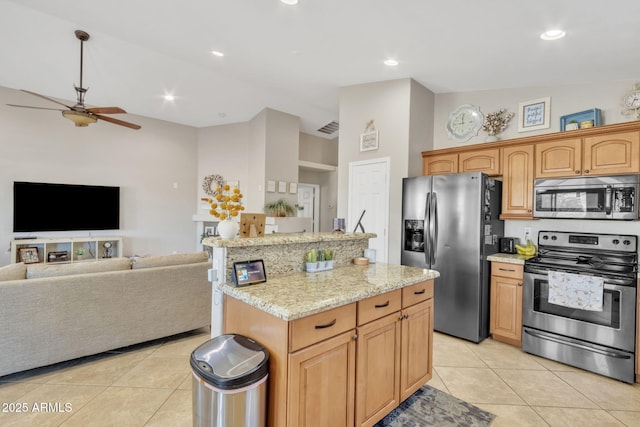 kitchen featuring a kitchen island, vaulted ceiling, appliances with stainless steel finishes, and light tile patterned flooring