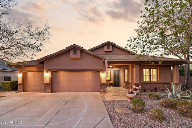 view of front facade featuring concrete driveway, brick siding, a garage, and stucco siding