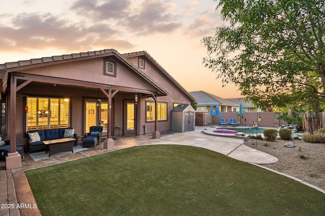 back of property at dusk with stucco siding, an outdoor hangout area, a fenced backyard, and a patio area