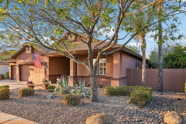 view of front facade featuring stucco siding, fence, concrete driveway, an attached garage, and brick siding