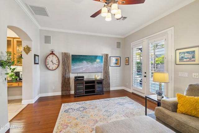 living room with arched walkways, wood finished floors, visible vents, and ornamental molding