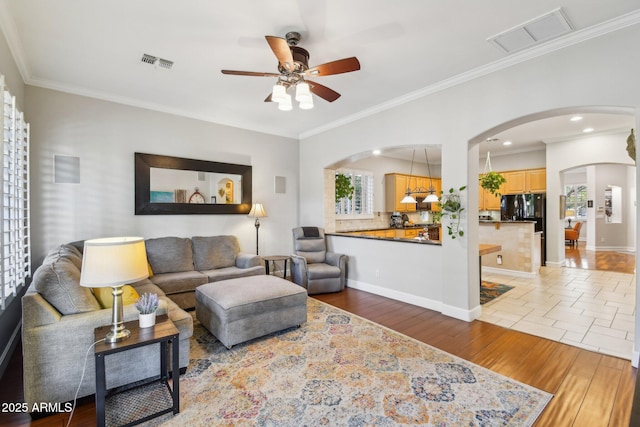 living room with visible vents, arched walkways, and wood finished floors