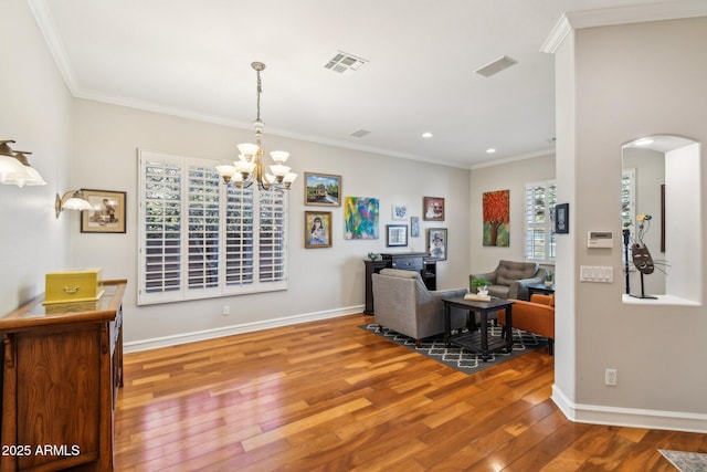 living area with visible vents, baseboards, ornamental molding, and hardwood / wood-style flooring