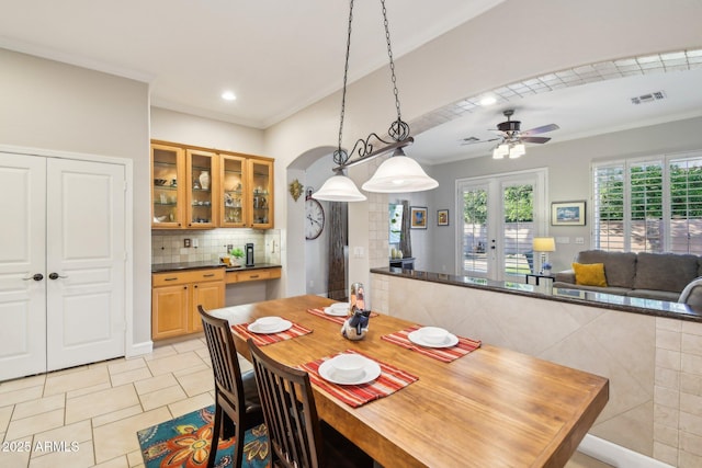 dining area featuring a ceiling fan, visible vents, arched walkways, ornamental molding, and french doors