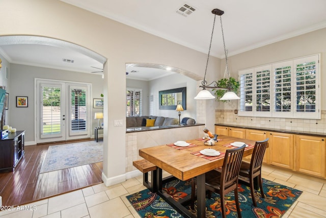 dining area featuring visible vents, french doors, arched walkways, crown molding, and light tile patterned floors