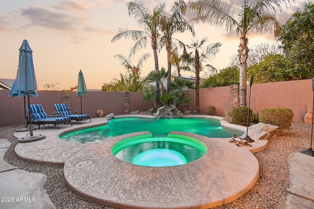 view of swimming pool featuring a patio area, a fenced backyard, and a pool with connected hot tub