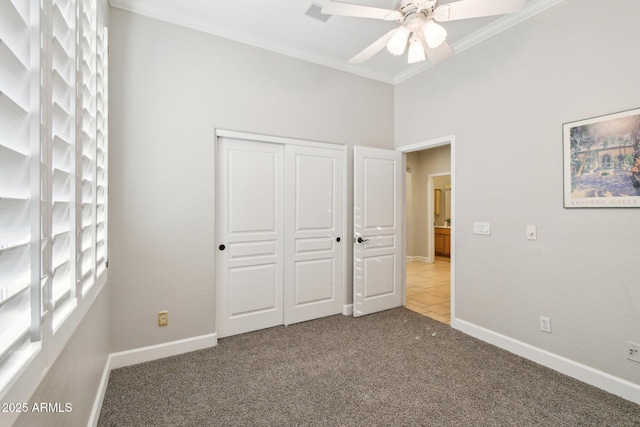 unfurnished bedroom featuring a ceiling fan, a closet, carpet floors, crown molding, and baseboards