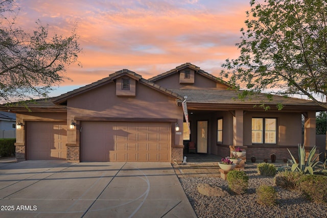 view of front of property with stucco siding, driveway, brick siding, and an attached garage