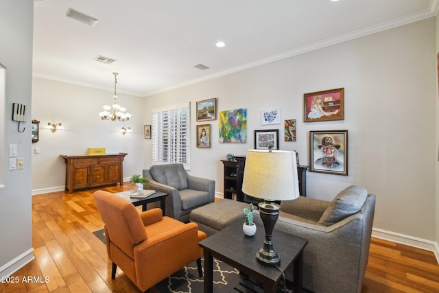 living area with visible vents, crown molding, baseboards, light wood-style floors, and a notable chandelier