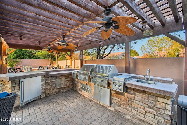 view of patio / terrace featuring a grill, exterior kitchen, fence, and a sink