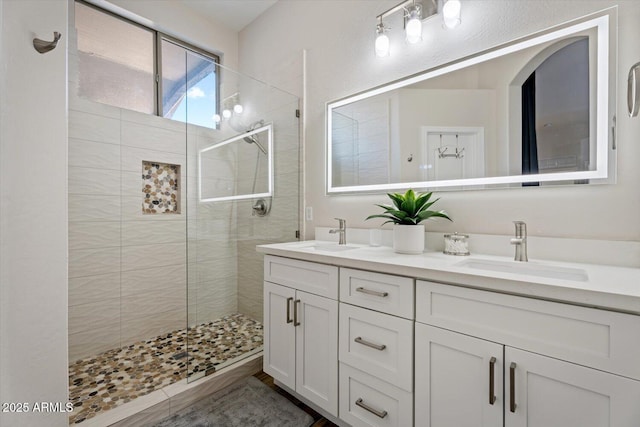 bathroom with a tile shower and vanity