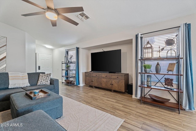 living room featuring light hardwood / wood-style floors, vaulted ceiling, and ceiling fan