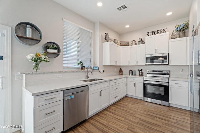 kitchen featuring white cabinets, sink, appliances with stainless steel finishes, and light hardwood / wood-style flooring