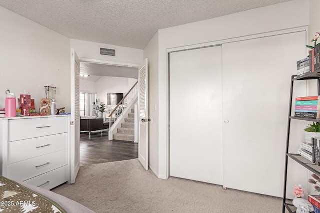 bedroom featuring a textured ceiling, carpet floors, a closet, and visible vents