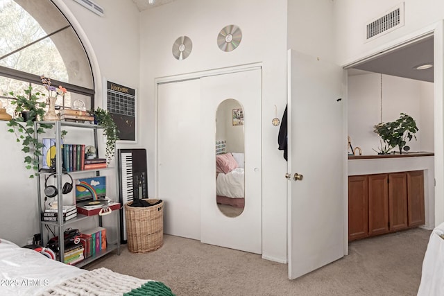 bedroom with light carpet, visible vents, and a closet