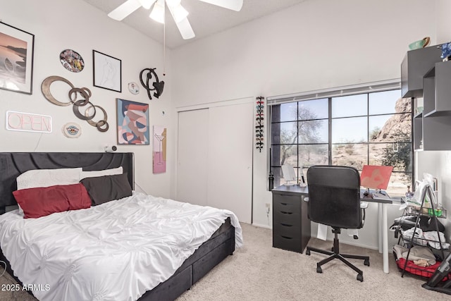 bedroom featuring a ceiling fan, a closet, light colored carpet, and a high ceiling