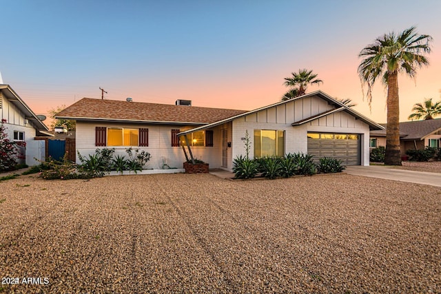 ranch-style home with brick siding, an attached garage, driveway, and board and batten siding