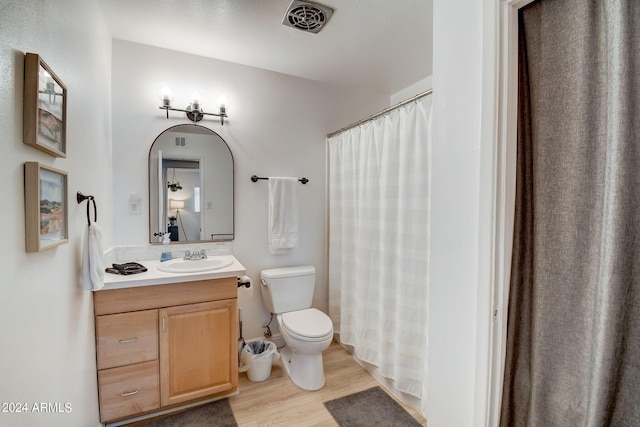 full bathroom with visible vents, toilet, vanity, and wood finished floors