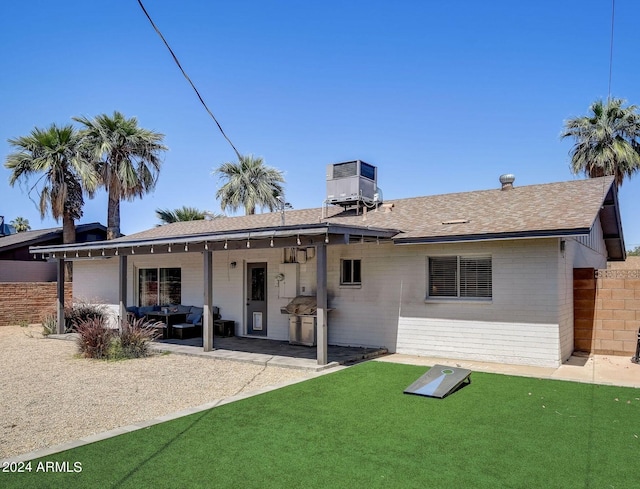 rear view of property with a patio, central AC unit, fence, a yard, and brick siding