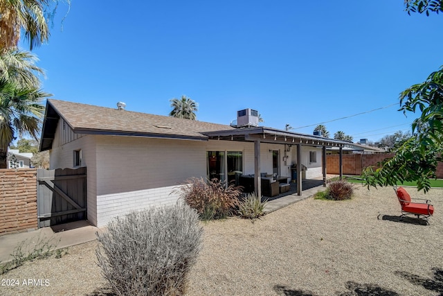 back of property featuring brick siding, fence, roof with shingles, a patio, and a gate