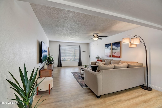 living area featuring baseboards, a textured ceiling, a ceiling fan, and light wood finished floors