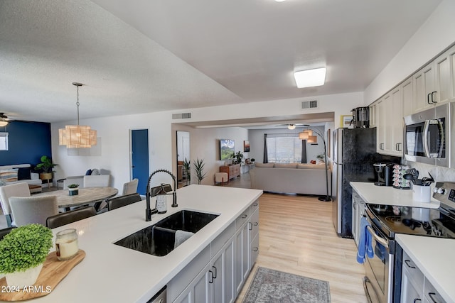 kitchen featuring visible vents, ceiling fan, open floor plan, stainless steel appliances, and a sink