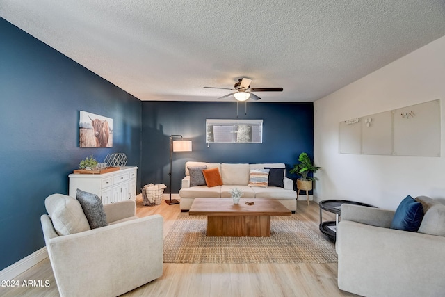 living area featuring baseboards, a textured ceiling, ceiling fan, and wood finished floors