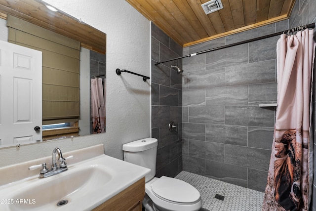 full bath featuring tiled shower, vanity, toilet, a textured wall, and wood ceiling