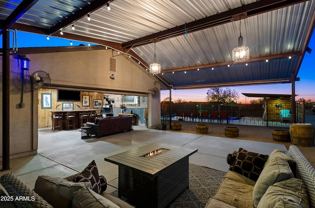 patio terrace at dusk with an outdoor living space with a fire pit and fence