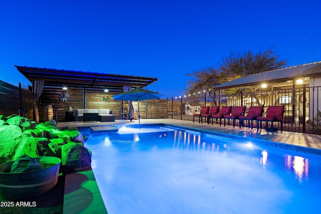 pool at night with outdoor lounge area and fence