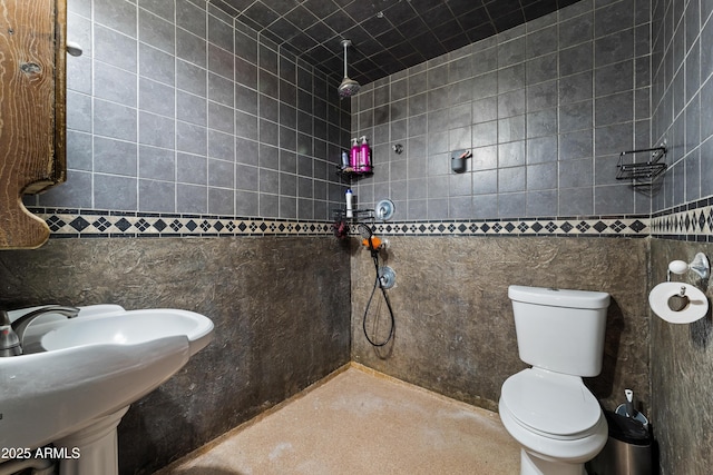 full bathroom featuring tiled shower and toilet